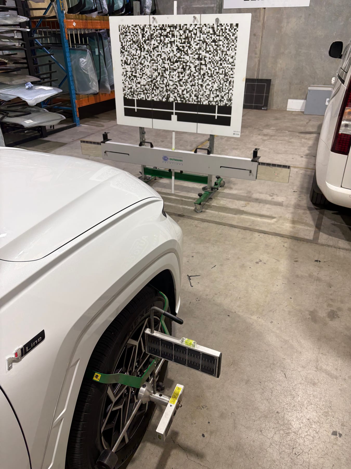A Volkswagen T-Roc set up for ADAS calibration with a target board and wheel-mounted gauge at the Morayfield Auto Glass workshop