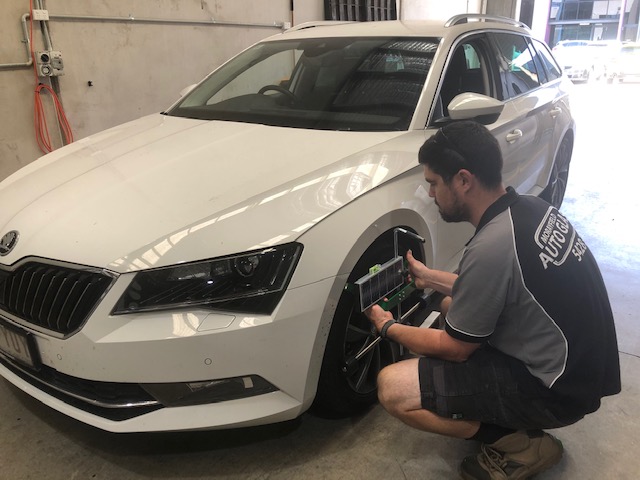 A technician calibrating a windscreen-mounted ADAS camera with diagnostic equipment