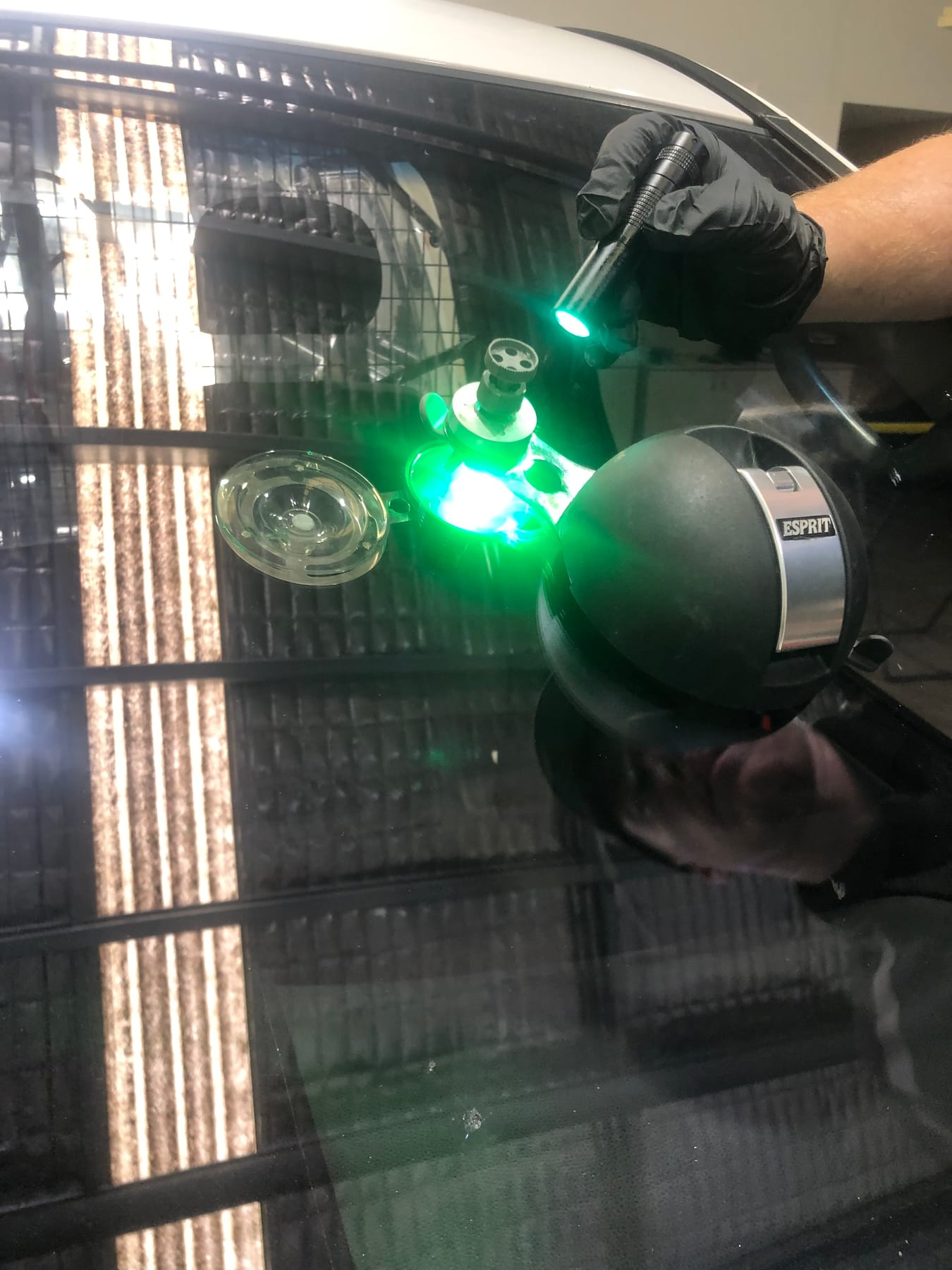 A windscreen stone chip being cured with a green UV lamp and resin injector during a Morayfield Auto Glass repair
