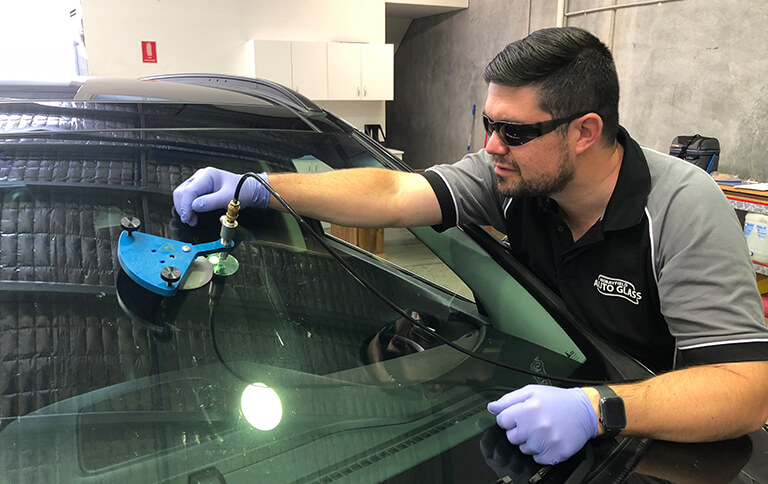 A Morayfield Auto Glass technician injecting resin into a windscreen stone chip with a repair tool